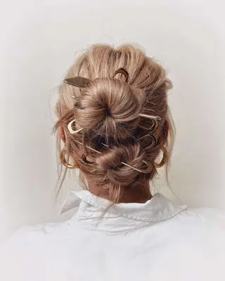 A model wearing double vertical buns with pins