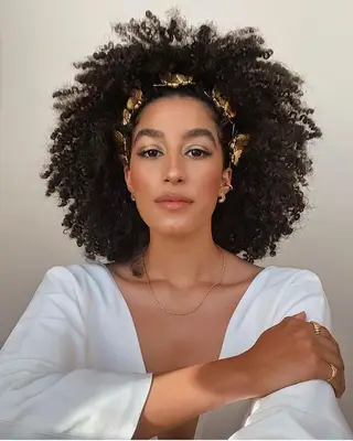A woman wearing her hair in a natural curly afro with gold headband