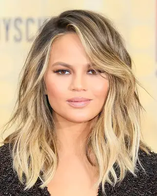 Chrissy Teigen blonde beach waves with side-swept bangs