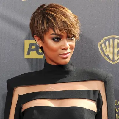 Tyra Banks attends an event, wearing a black outfit with sheer details and a modern hairstyle