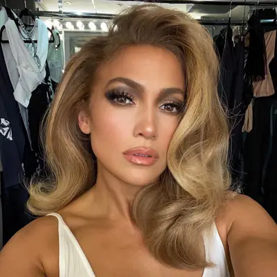 Jennifer Lopez taking a portrait photo indoors, wearing styled hair and makeup