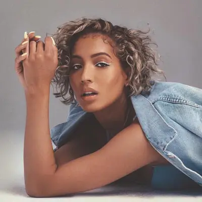 Music artist Marissa wears a curly ash blonde bob