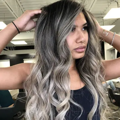Woman with gray-toned ash blonde balayage hair with dark roots