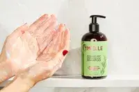 A person lathering the Mielle Rosemary Mint Strengthening Shampoo in their hands