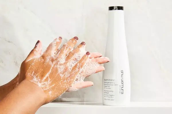 a person lathering Shu Uemura Izumi Tonic Strenghtening & Thickening Rice Water Shampoo in their hands