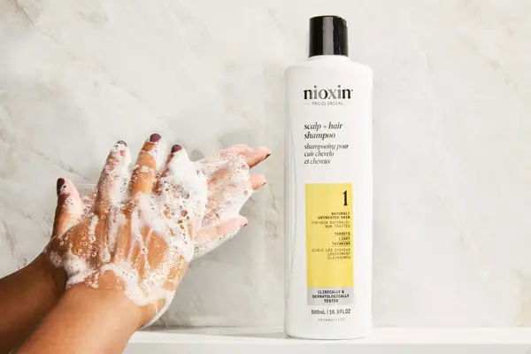 A person lathering the Nioxin System 1 Shampoo in their hands