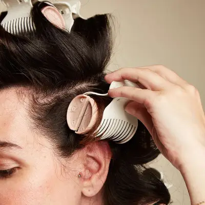 Model clipping a roller in her long hair