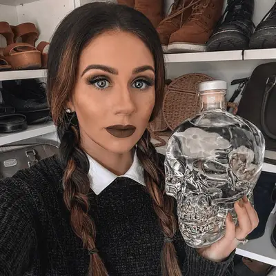 Woman with long braids and Wednesday Addams costume holding glass skull jar