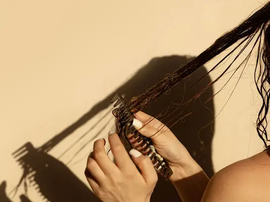 woman combing through wet hair 