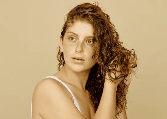 Woman scrunching up her curly red hair 