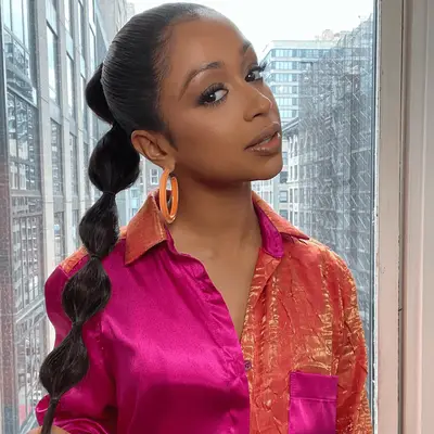 Liza Koshy wears a high bubble ponytail and pink and orange outfit