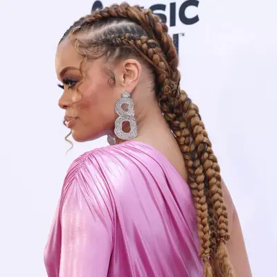 Andra Day with intricate braided hairstyle and large earrings at an event