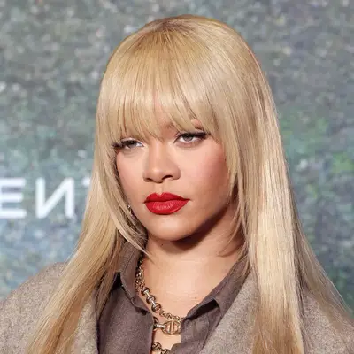 Rihanna wears a subtle clip in bang with face framing edges to blend into her blonde layers