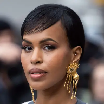 Sabrina Dhowre Elba wears a subtle side part on her thin fringe with an updo and large earrings at Paris Fashion Week