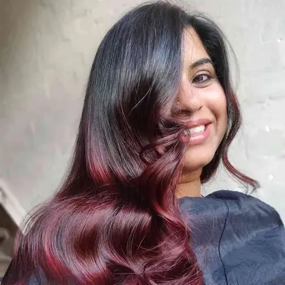 Woman with plum-toned ombre mahogany hair color with soft curls