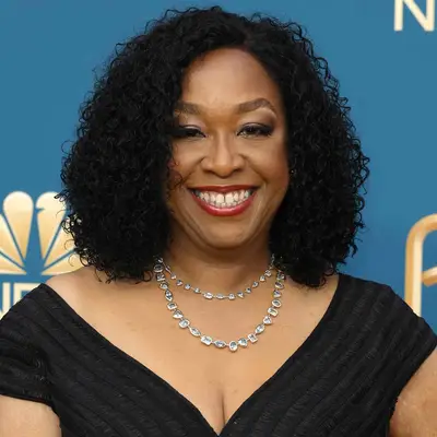 Shonda Rhimes wears a shoulder-length shaped curly hairstyle