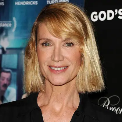 Kelly Lynch wears a tousled long bob hairstyle with side-swept bangs and deep side part