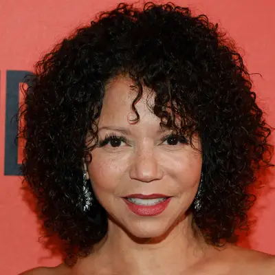 Gloria Reuben wears a curly shag hairstyle with bangs