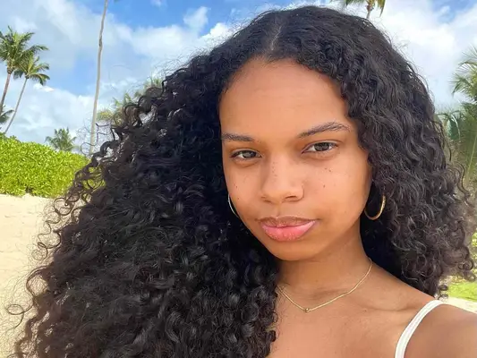 MYM Beauty editor Olivia Hancock with defined curls blowing in wind on beach