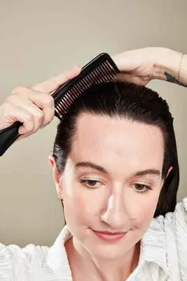 A woman combs gel into her hair