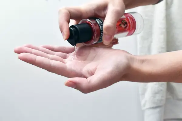 photo of a person pumping the john frieda frizz ease hair serum into their hand