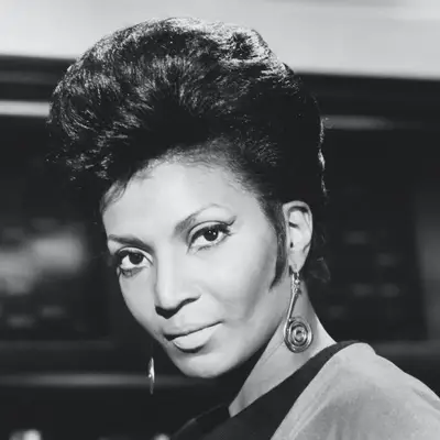 Nichelle Nichols wears a voluminous pixie cut with sideburns in the 1960s