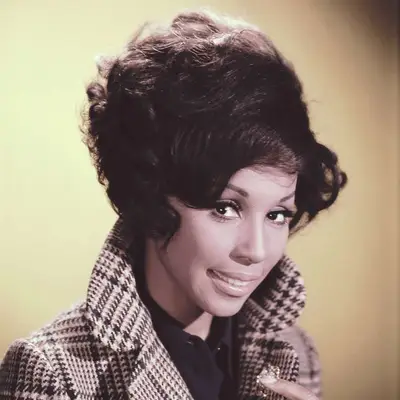 Diahann Carroll wears a short, curly hairstyle with side-swept bangs