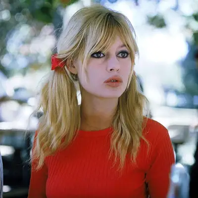 Brigitte Bardot wears blonde pigtails with curtain bangs and red ribbons