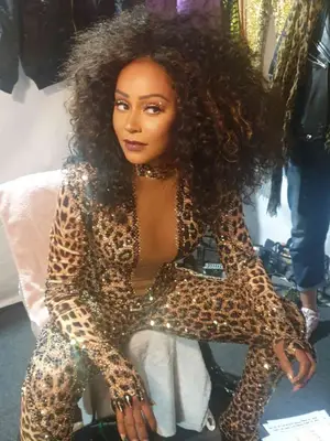 scary spice with curly hair wearing leopard print sequin jumpsuit