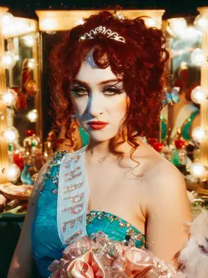 chappell roan with red curly hair piled on top of head with silver crown