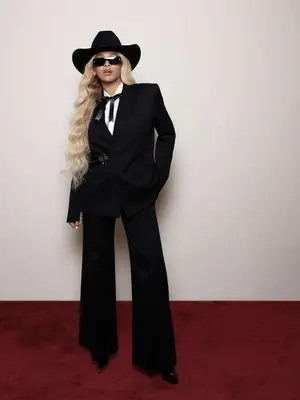 Beyoncé wearing black cowboy hat, black sunglasses, black suit, long blonde curly hair