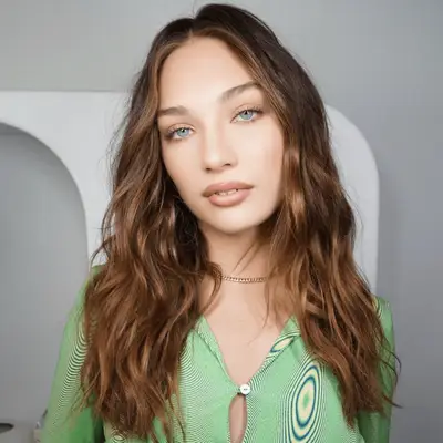 Maddie Ziegler with wavy chestnut hair and honey highlights.
