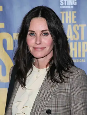 Courteney Cox with middle-parted tousled waves wearing a blazer