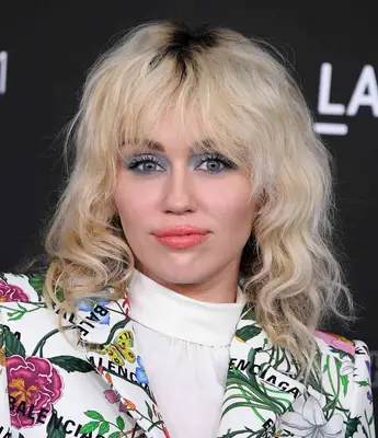 Miley Cyrus with blonde curly shag haircut and floral suit at the 10th Annual LACMA ART+FILM GALA 