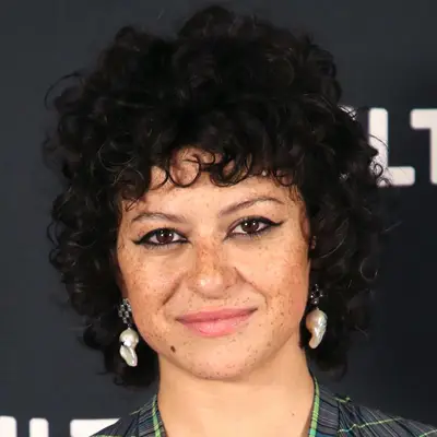 Alia Shawkat wears a cropped curly wolf cut hairstyle