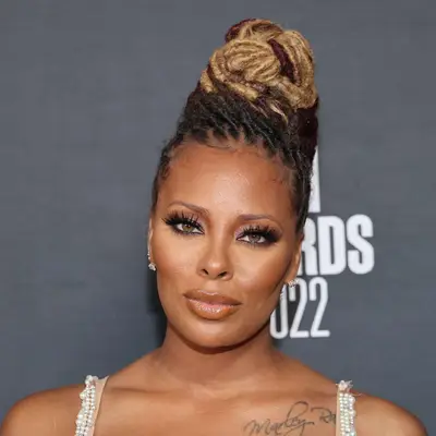 Eva Marcille wears locs with dark roots and blonde ends in a twisted updo