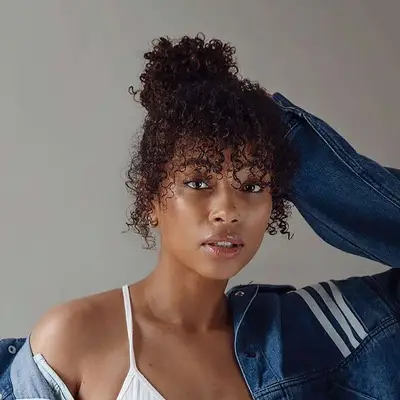 Close up of a woman with faux curly bangs and a high bun