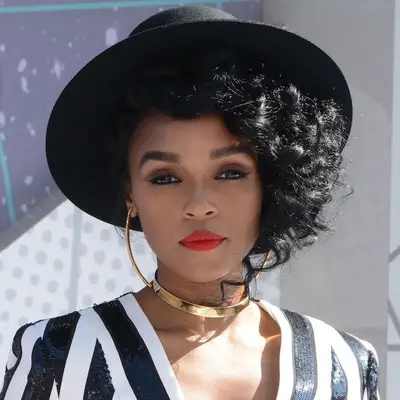 Janelle Monáe with curly side-parted and shaved hairstyle and a large black hat at the 2016 BET Awards in Los Angeles, California