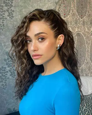 Close up of actor Emmy Rossum with deeply parted curly hair