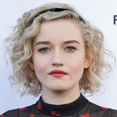 Julia Garner with a short curly hair and a black headband at the 2019 