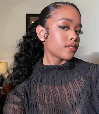 Close up of singer H.E.R. with a slicked back curly ponytail