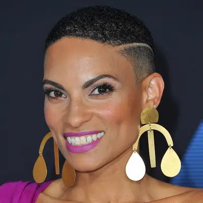 Singer Goapele wears ornamental earrings beneath her tightly faded buzz cut and a bright magenta lip to match her dress
