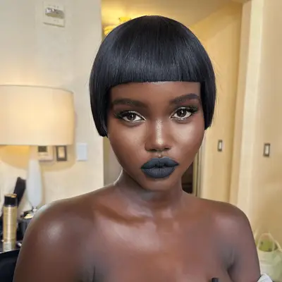 Sabrina Elba wears a long, thick pixie with uneven feathered bangs, red lips and a chunky earring while attending Paris Fashion Week