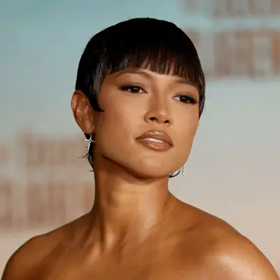 Karrueche Tran attends an event with a long, straight bang, curled sideburns and slick, elongated cut above exposed shoulders