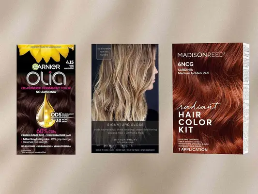 Three different boxes of drugstore hair dyes on a tan, textured background, including Garnier Olia Oil Permanent Hair Color