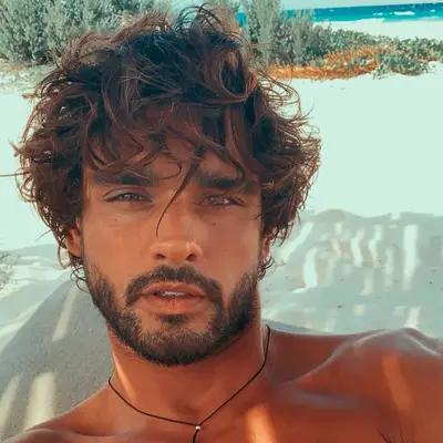 Marlon Teixera wears a tousled wavy haircut