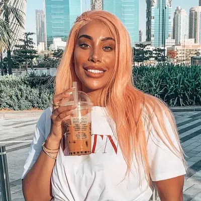 Woman with long peach hair wig and a cup of boba tea