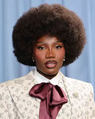 A person with a styled afro hairstyle wearing formal attire