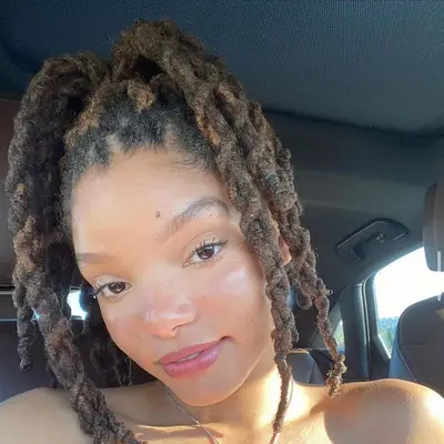 Halle Bailey wears long twisted locs in a high ponytail and subtle radiant makeup