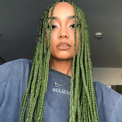 A woman with long braided green hair and a necklace